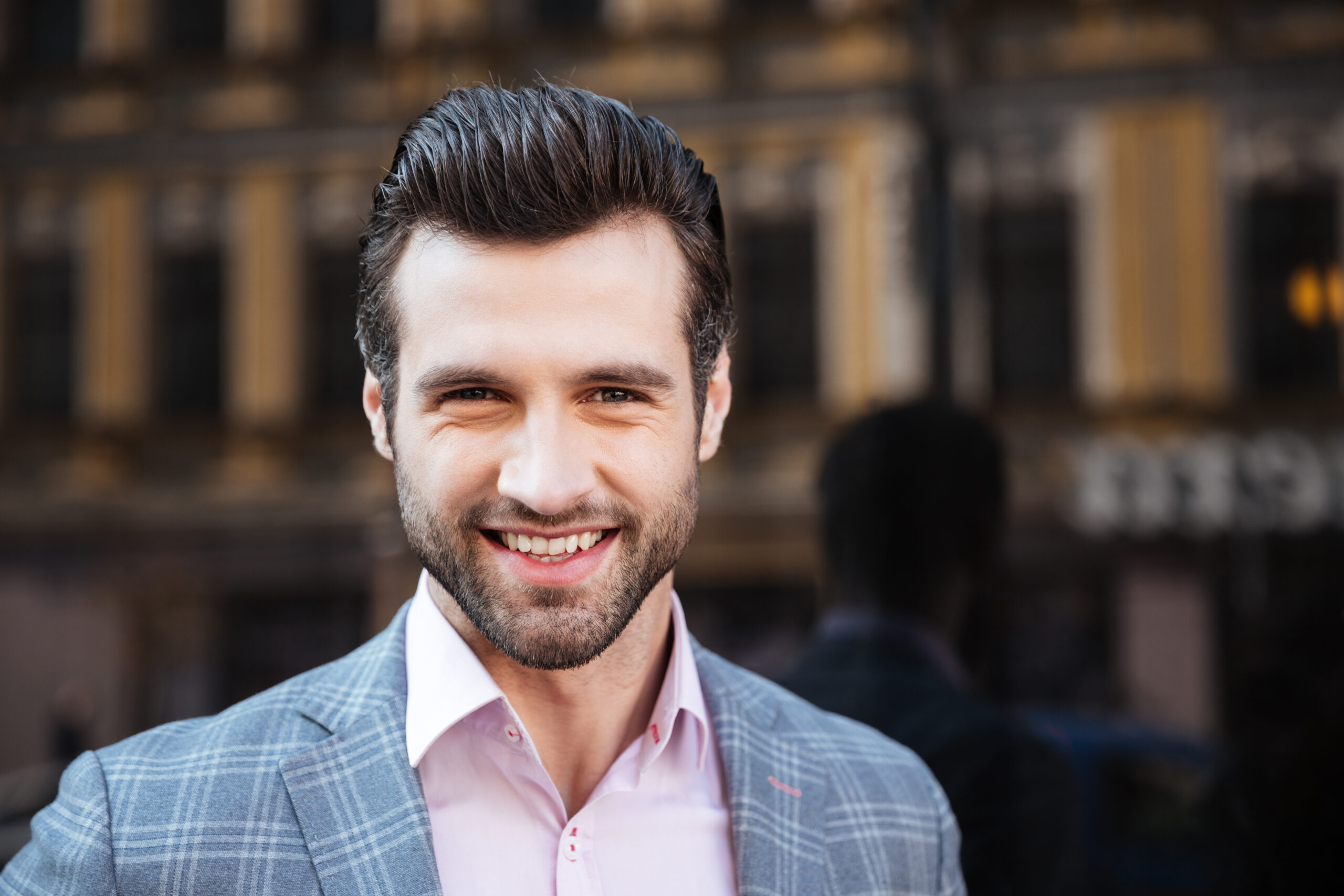 Smiling handsome man in a jacket looking at camera Close up portrait of a smiling handsome man in a jacket looking at camera in a city area